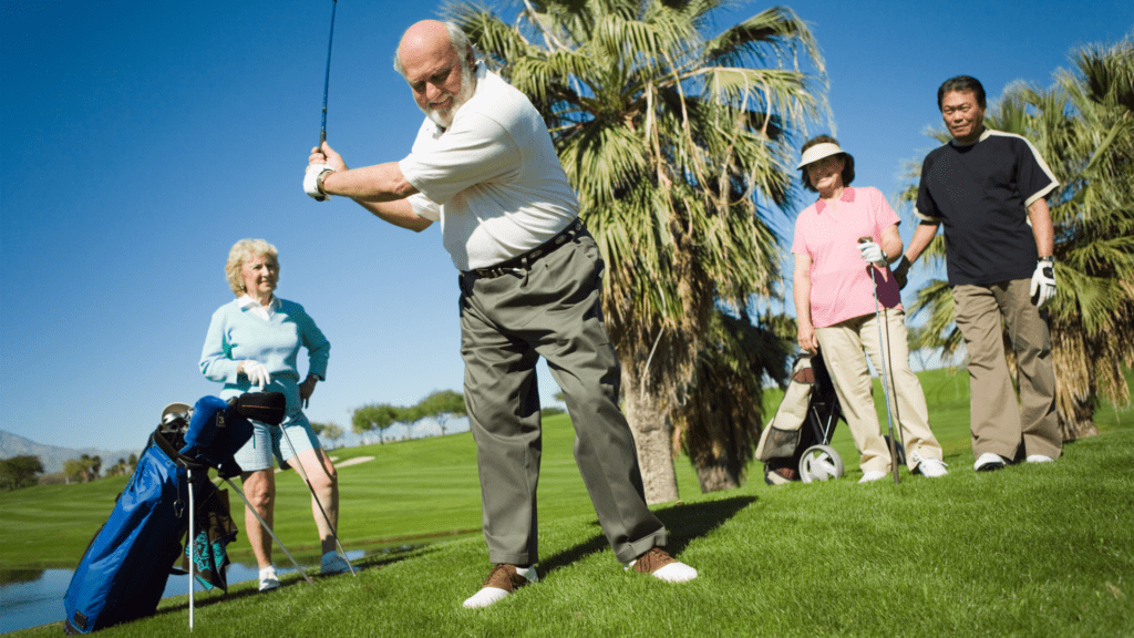 how to rebuild a golf swing as you age - shows senior golfer being observed by three golfers as he swings the club.  