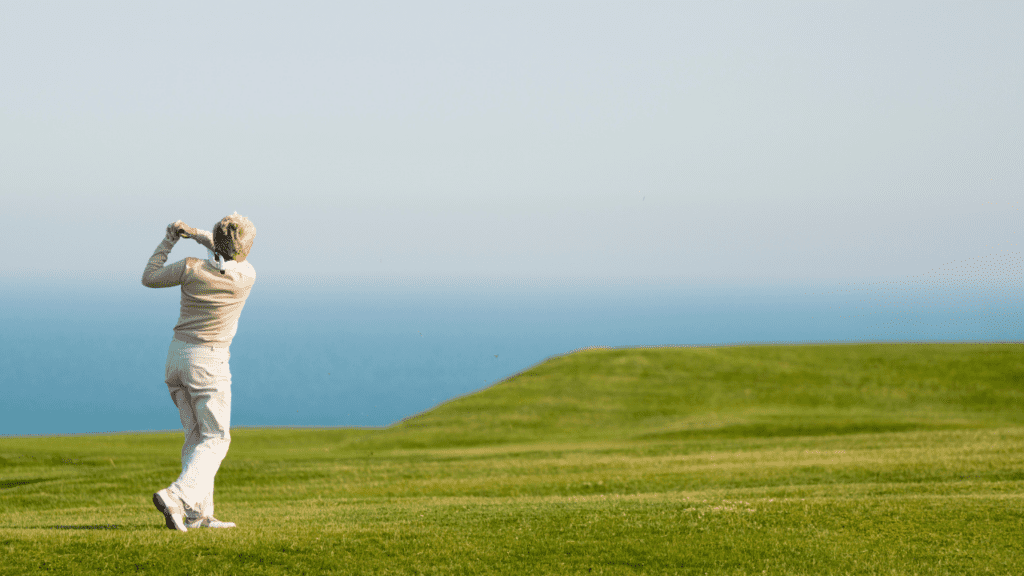 budget golf trips showing a woman golfer teeing off on a beautiful ocean course.