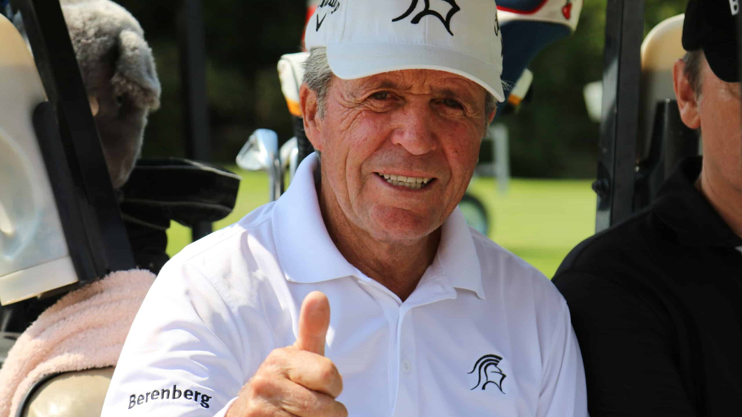 gary player fitness routine keeps him active. Show here in his 80's and in shape wearing all white, and has a smile with a thumbs up.