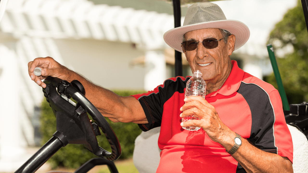 best golf hats for sun protection; showing senior golfer wearing a golf sun hat sitting in his golf cart drinking water between holes.