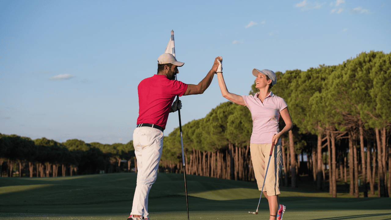 why is golf so fun article: showing two golfers on the green doing a high five after a good hole.