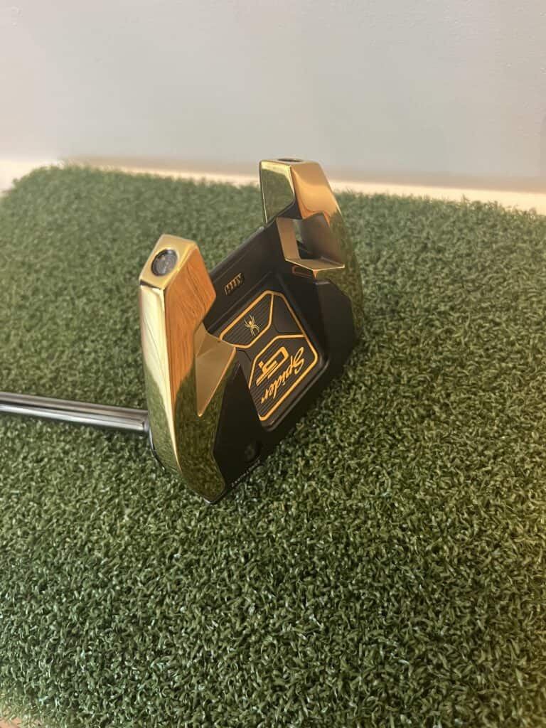 TaylorMade Spider GT Putter laying on its side.  Beautiful black and gold coloring.