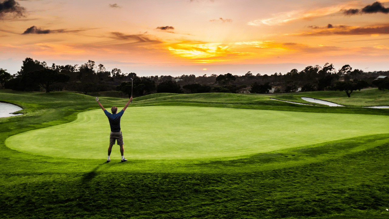 Golfer raising his hands above his head in joy after a good round of golf on the putting green.