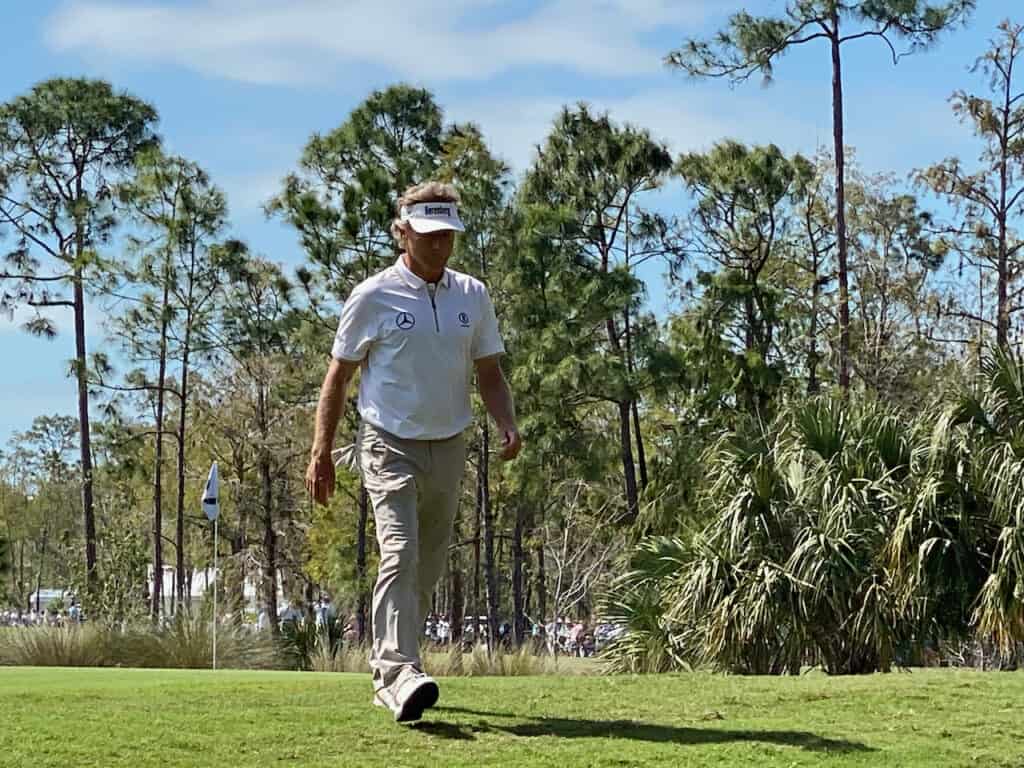Bernhard Langer 2023 Chubb Classic in Naples, FL walking off the golf course with green behind him.