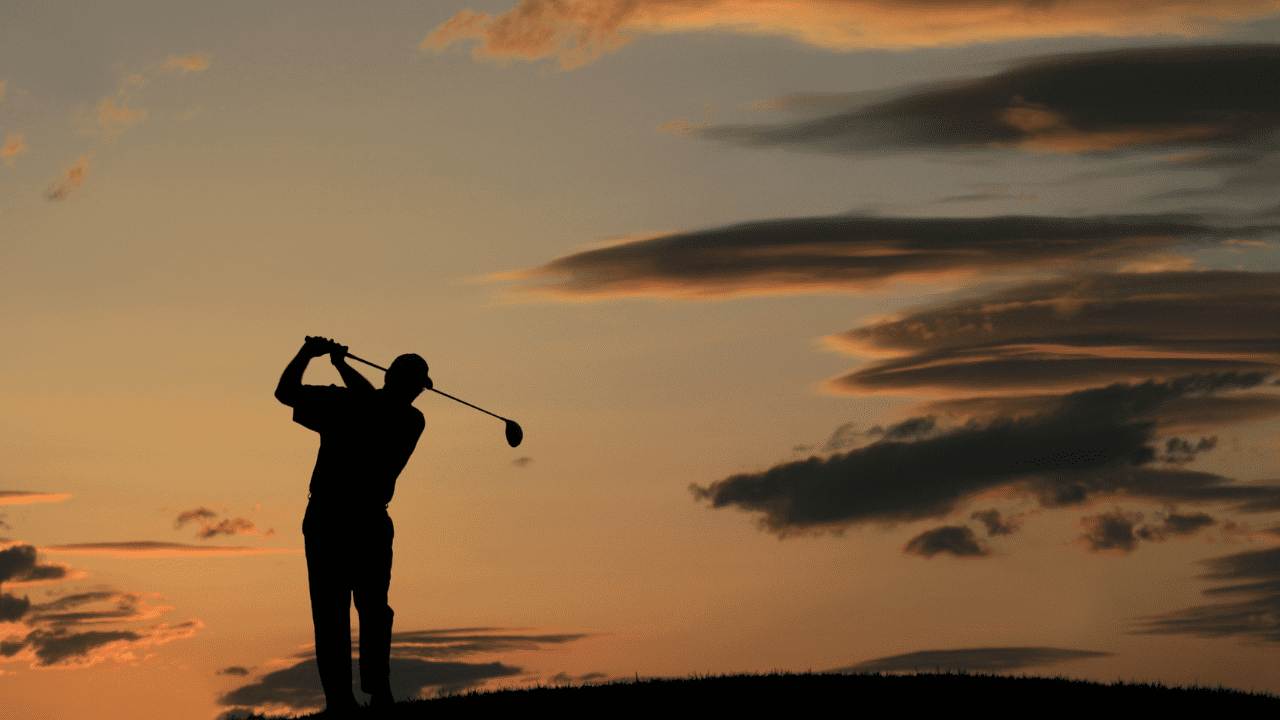 Golfer hitting into the sunset showing his golf swing.