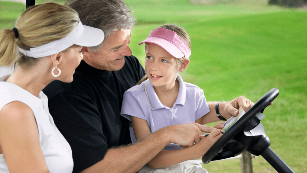 Granddaughter sitting our her grandfather's lap. Looking at a scorecard with her grapndparends in a golf cart.