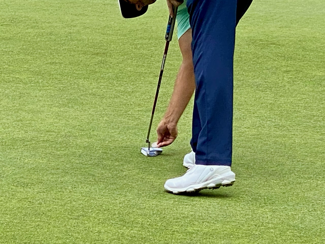 Padraig Harrington marking his ball with Odyssey putter and Foot Joy golf shoes